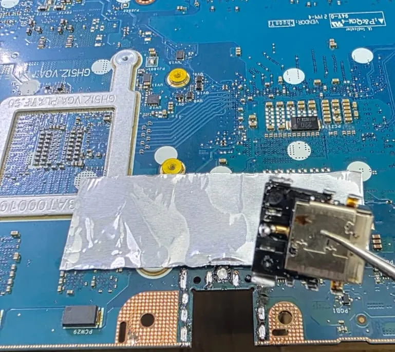 Conector de energia do Acer Nitro 5 sobre a placa, protegida por uma tira de papel alumínio, enquanto a solda é aquecida com uma ponta