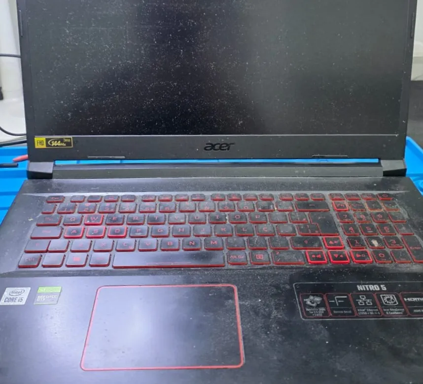 Acer Nitro 5 AN517 aberto na bancada, com o teclado de teclas pretas e letras vermelhas iluminado e o logotipo da Acer na base da tela