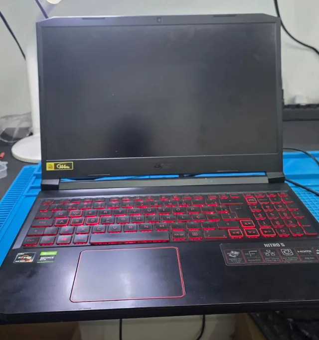 Notebook Acer Nitro 5 ligado na bancada com o teclado iluminado em vermelho e a tela completamente preta