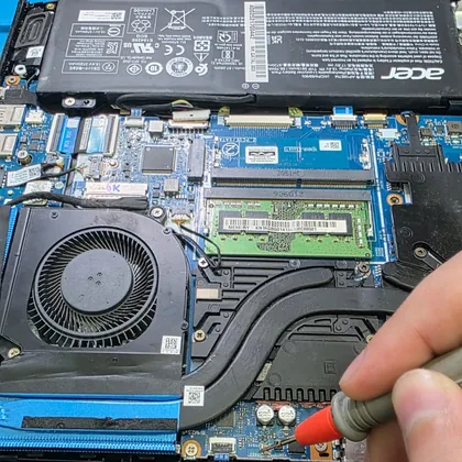 Técnico medindo com a ponta do multímetro a placa-mãe de um Acer Predator Helios 300 aberto na bancada