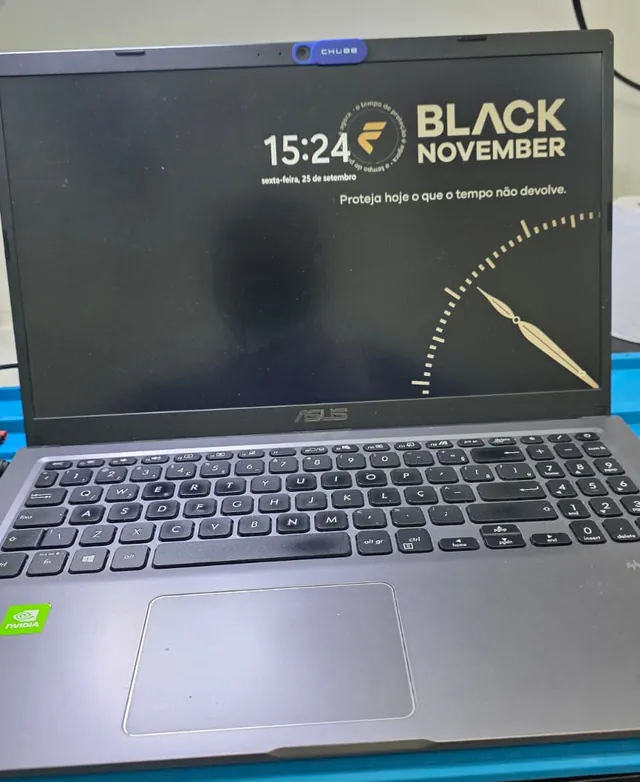 Notebook ASUS X515J ligado na bancada depois do reparo, com o relógio e o papel de parede na tela