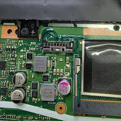 Região do conector da bateria de um ASUS X515J com fios de reparo soldados sobre a placa-mãe verde