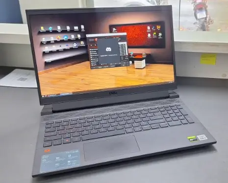 Notebook Dell G15 preto ligado sobre a bancada, com a área de trabalho do Windows aberta na tela
