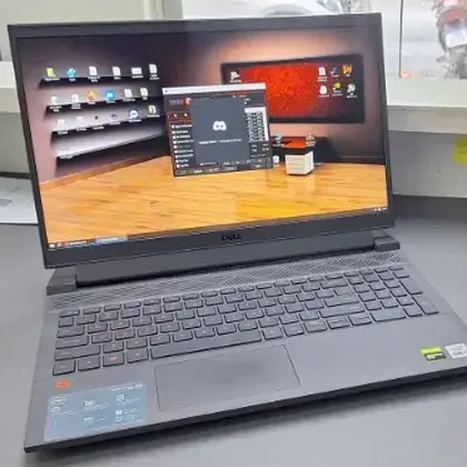 Dell G15 preto ligado na bancada da assistência, com a área de trabalho do Windows aberta na tela