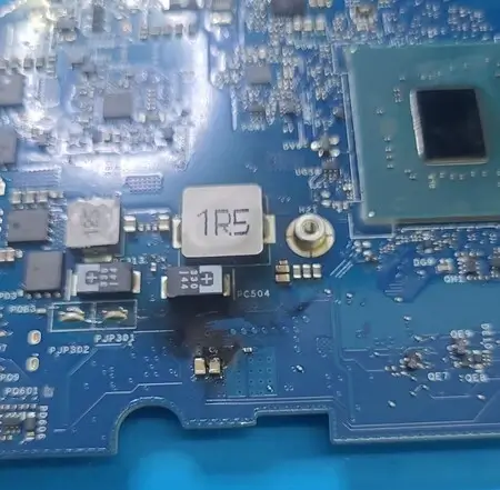 Placa-mãe de Dell G15 com mancha escura de queimado ao lado de um indutor marcado 1R5, no estágio de um regulador de tensão
