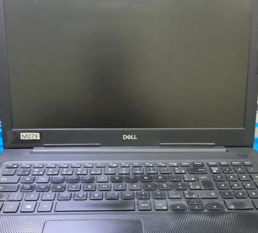 Dell Inspiron 3583 aberto na bancada com a tela preta, o teclado ABNT2 e uma etiqueta de identificação colada abaixo da tela