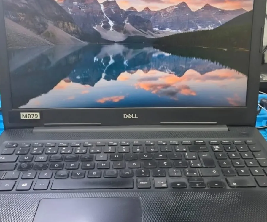 Dell Inspiron 3583 ligado, com um papel de parede de montanhas e lago refletido na tela e o teclado ABNT2 à frente