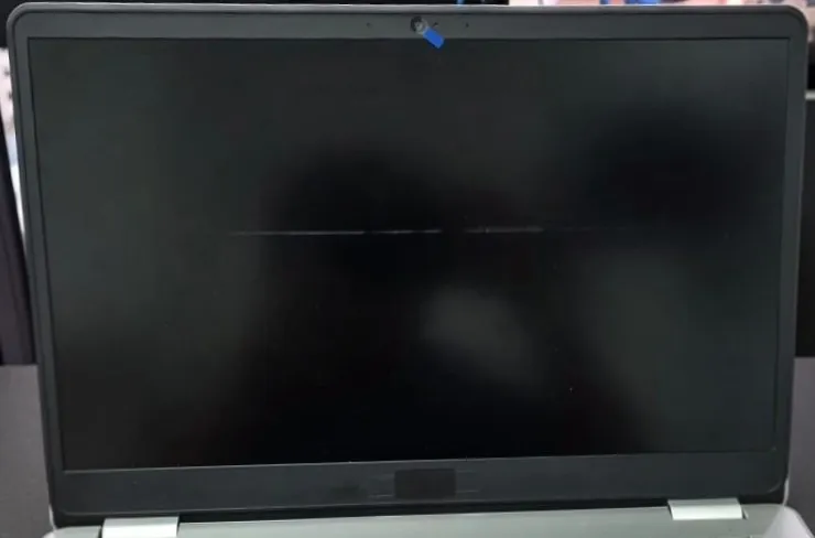 Dell Inspiron 5584 com a moldura preta em volta da tela, a tela totalmente escura exceto por uma linha fina e clara na horizontal, e um adesivo azul sobre a câmera