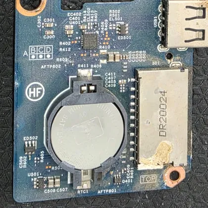Placa filha de um Dell Inspiron 5584 com a bateria do relógio e o leitor de cartão, com sinais de oxidação