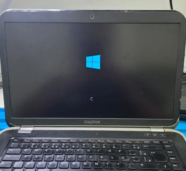 Dell Inspiron 7520 na bancada iniciando o Windows depois do reparo, com o ícone de carregamento na tela