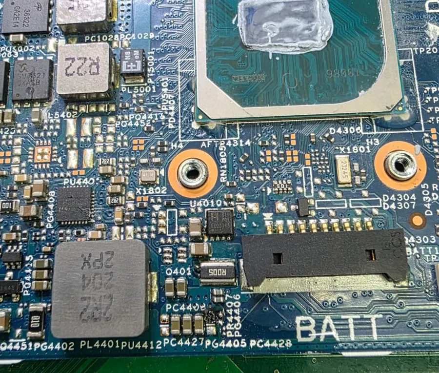 Detalhe da placa do Dell Latitude 3420 na região do conector da bateria, com indutor, transistores e capacitores do circuito de carga e a numeração impressa na placa