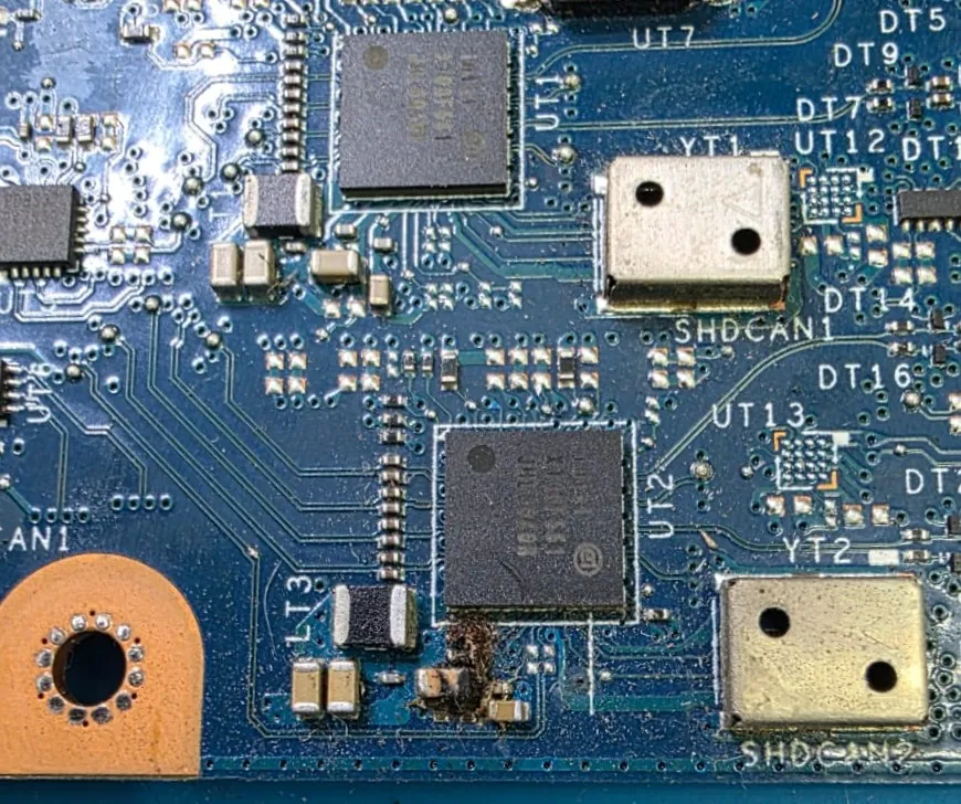 Placa-mãe do Dell Latitude 5420 em detalhe, com dois chips e dois cristais metálicos, e uma mancha escura de queima ao lado de um componente na parte inferior