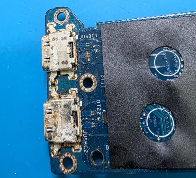Placa filha com duas portas USB-C de um Dell Latitude 5420, com as portas e as soldas cobertas de oxidação e resíduo