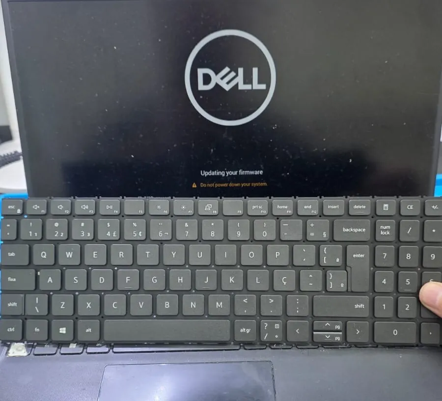 Dell Vostro 3510 ligado com a tela mostrando o logotipo da Dell e a mensagem de atualização de firmware, com um teclado ABNT2 posicionado sobre a base