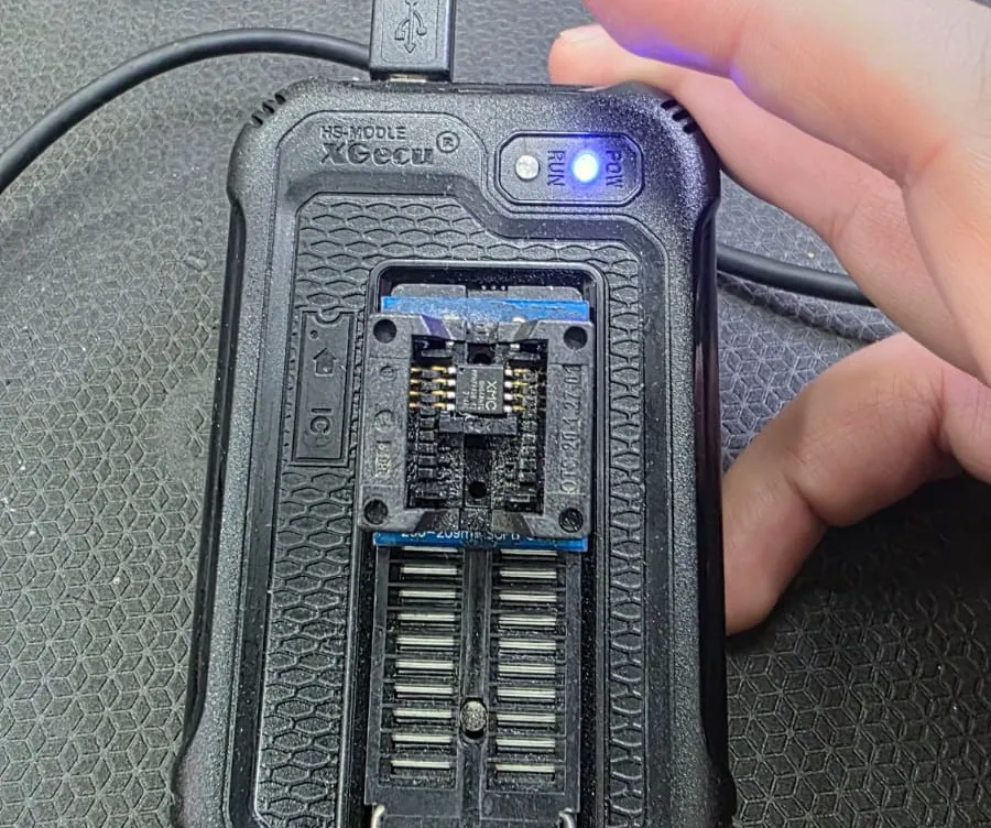 Programador de memórias XGecu T48 com um chip de BIOS de oito pinos encaixado no adaptador SOIC8, com a luz azul de funcionamento acesa
