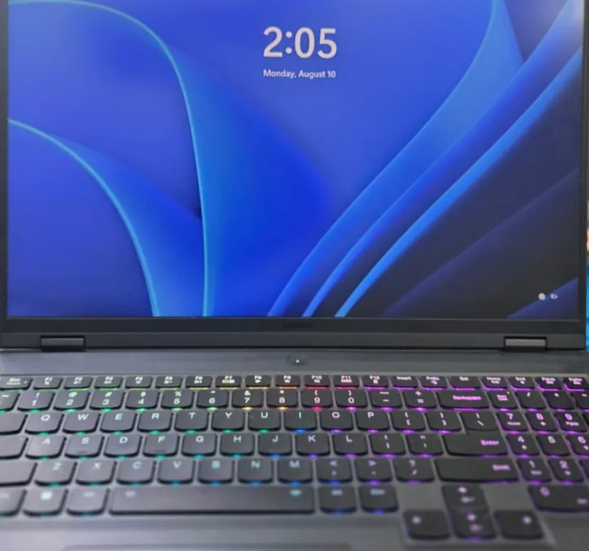 Lenovo Legion Pro 7 na bancada com a tela de bloqueio do Windows e o teclado iluminado em RGB depois do reparo