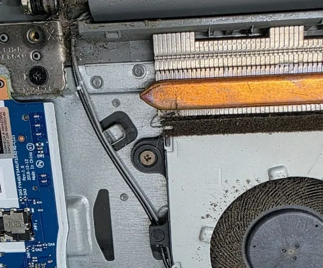 Dobradiça, aletas do dissipador e borda da ventoinha de um Lenovo IdeaPad S145 com poeira acumulada
