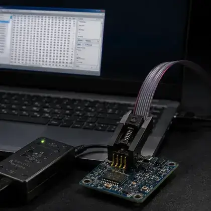 Clipe de gravador preso ao chip da BIOS de uma placa, com o editor hexadecimal do dump aberto na tela do notebook